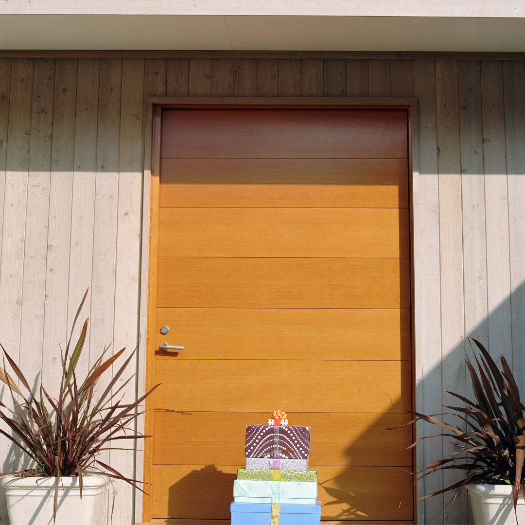 Wooden door with 5 stacked gifts sitting in front